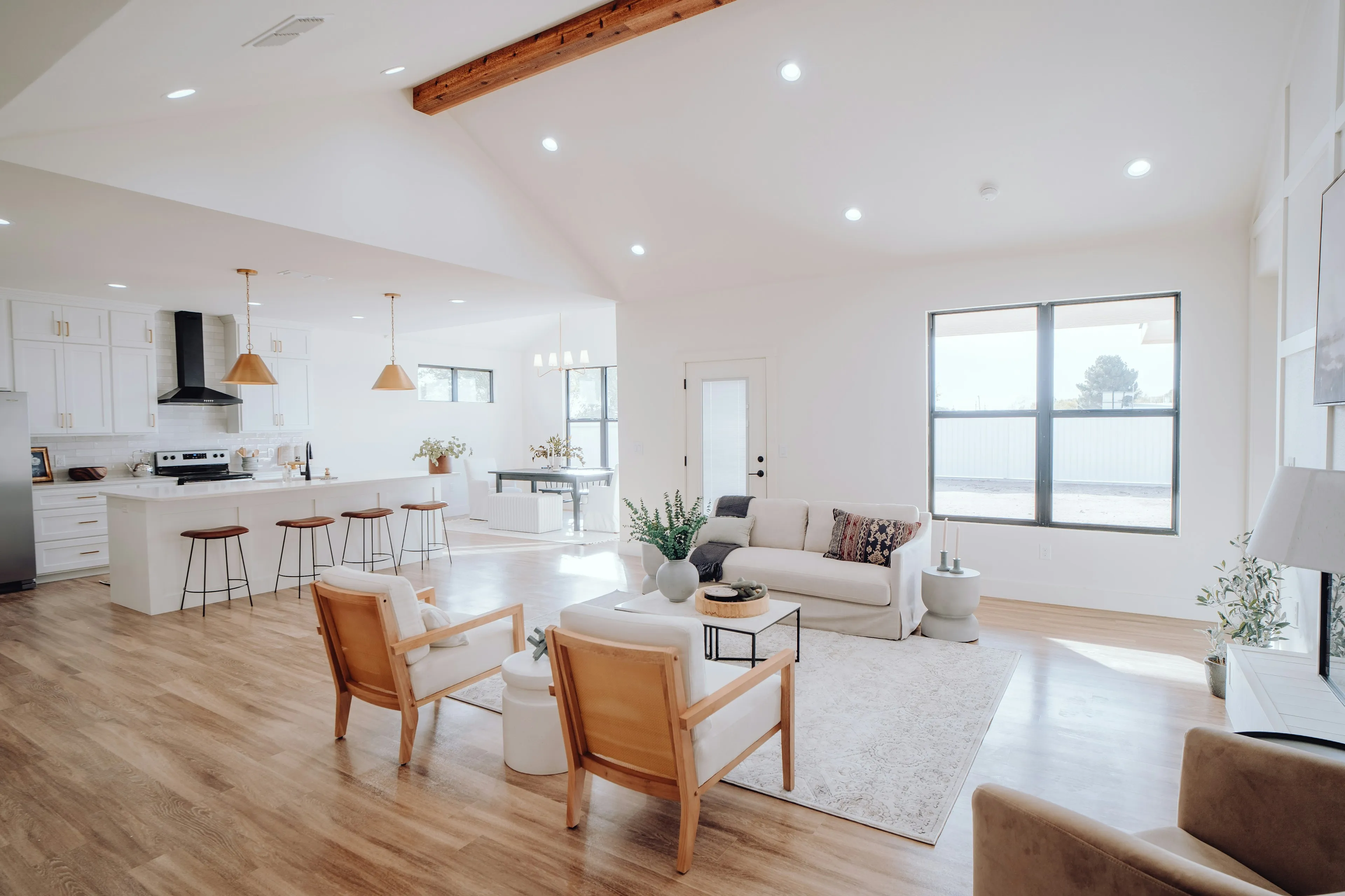 Open-plan kitchen and living room with wooden armchairs under a timber beam