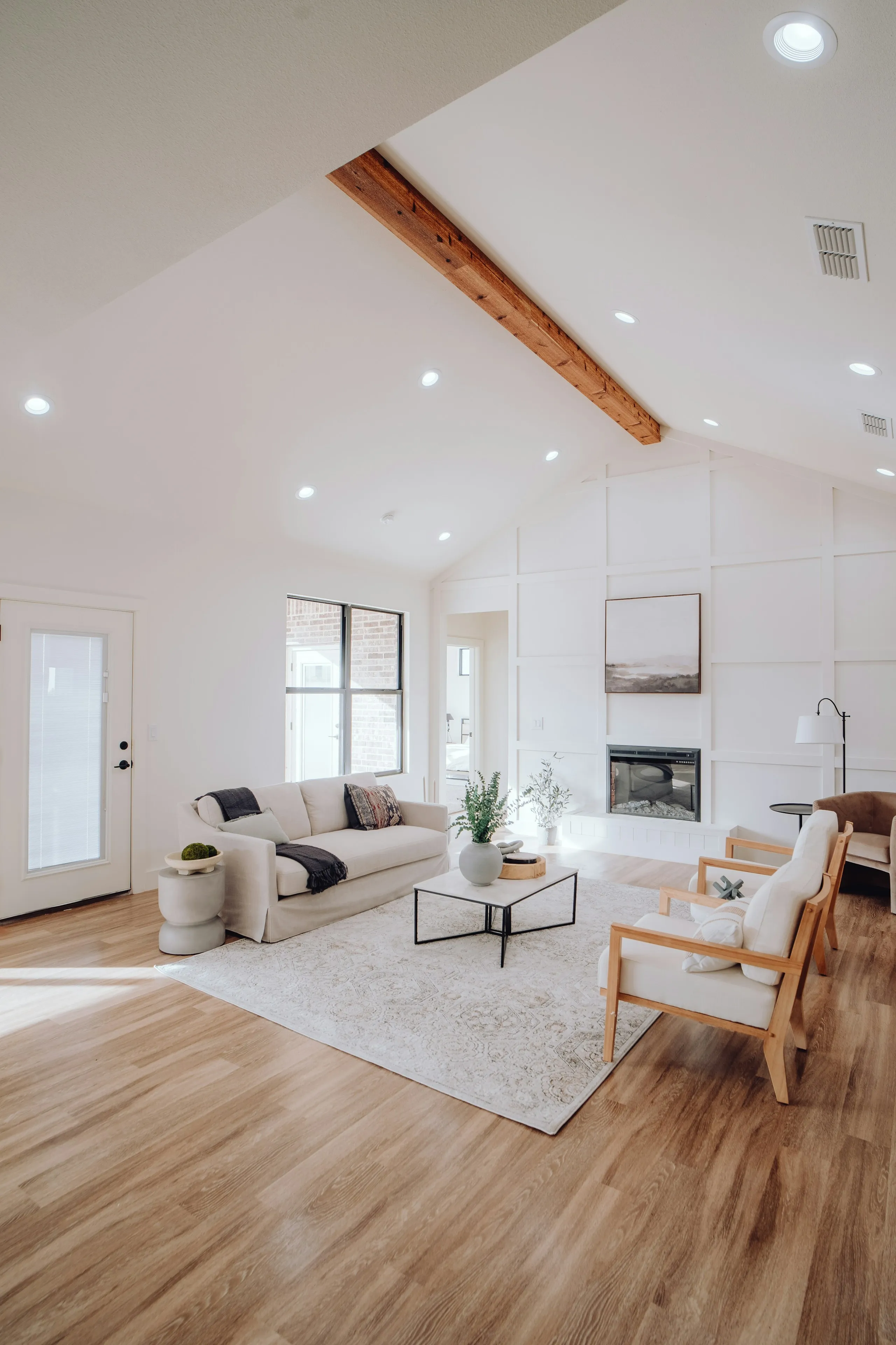 Living area with a timber ceiling beam, a sofa, wooden armchairs and a fireplace
