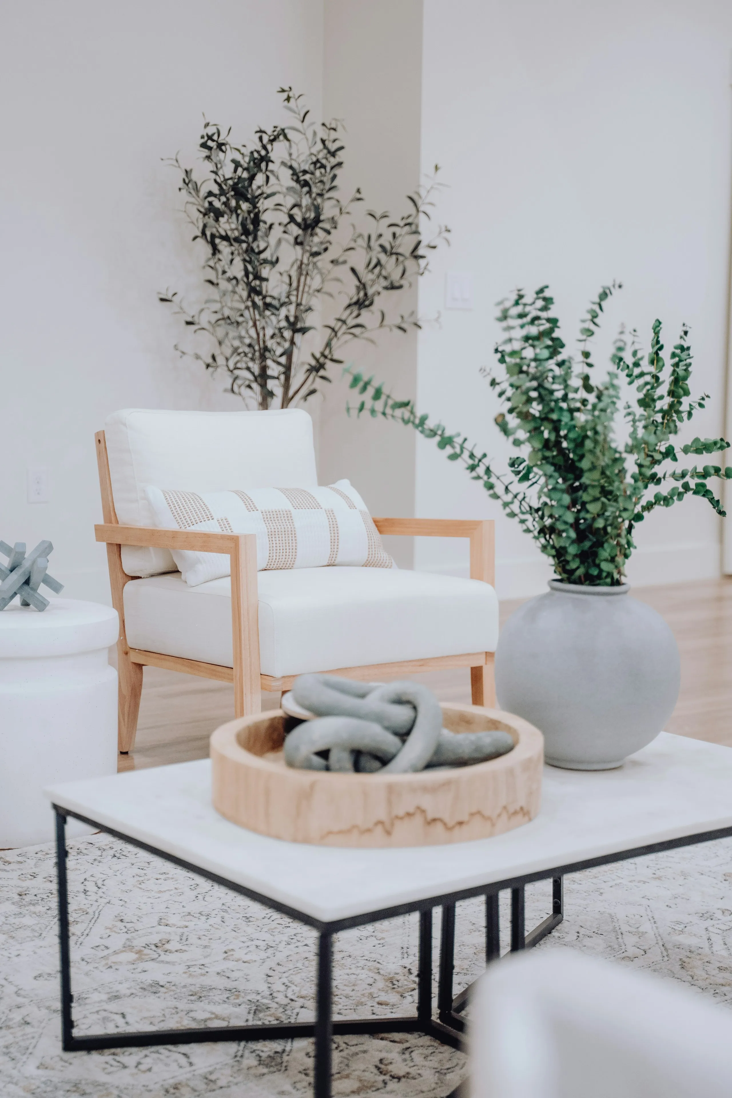 White armchair with a wooden frame beside a low table with plants
