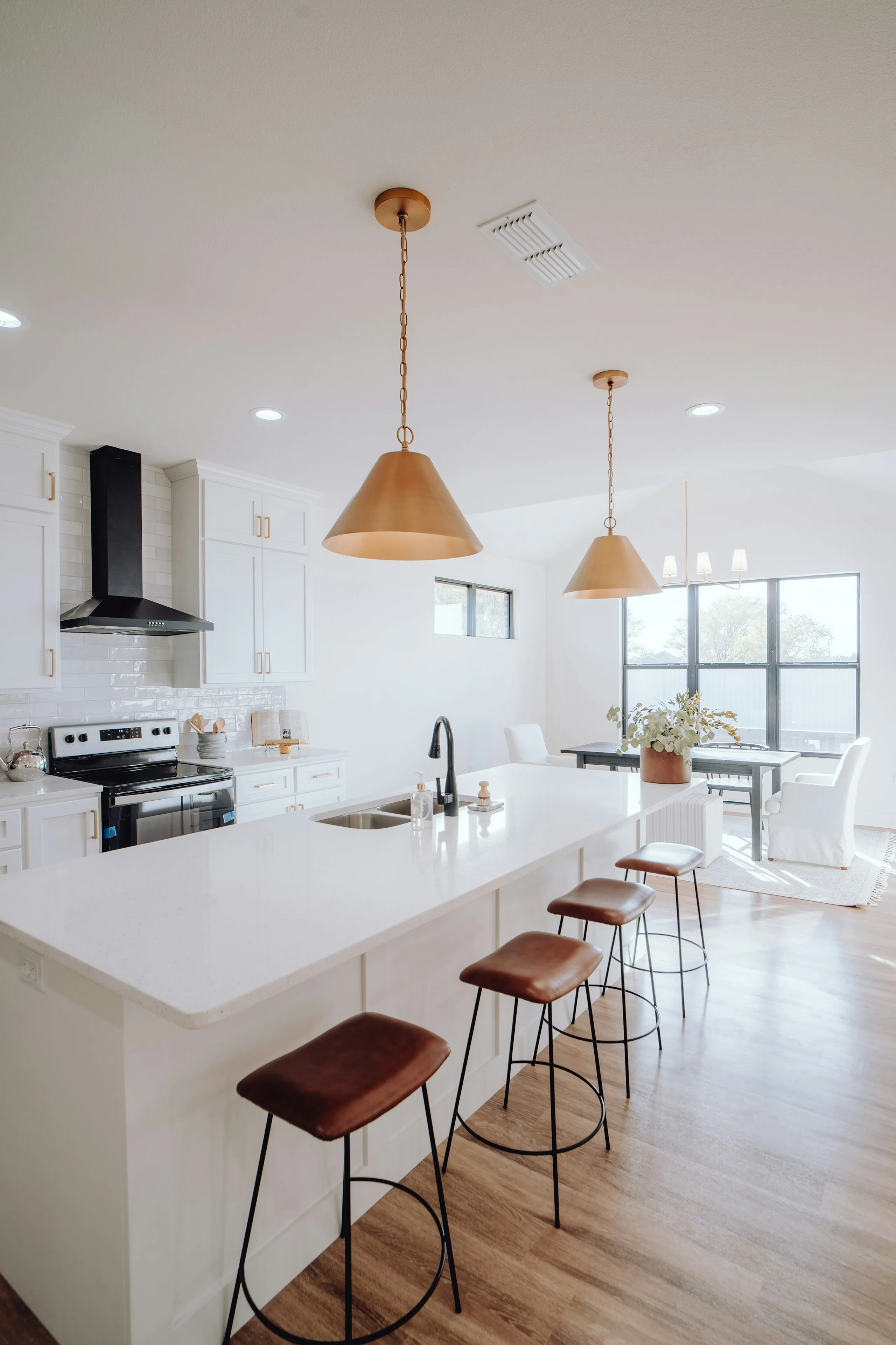 Kitchen island with leather bar stools under a copper pendant light