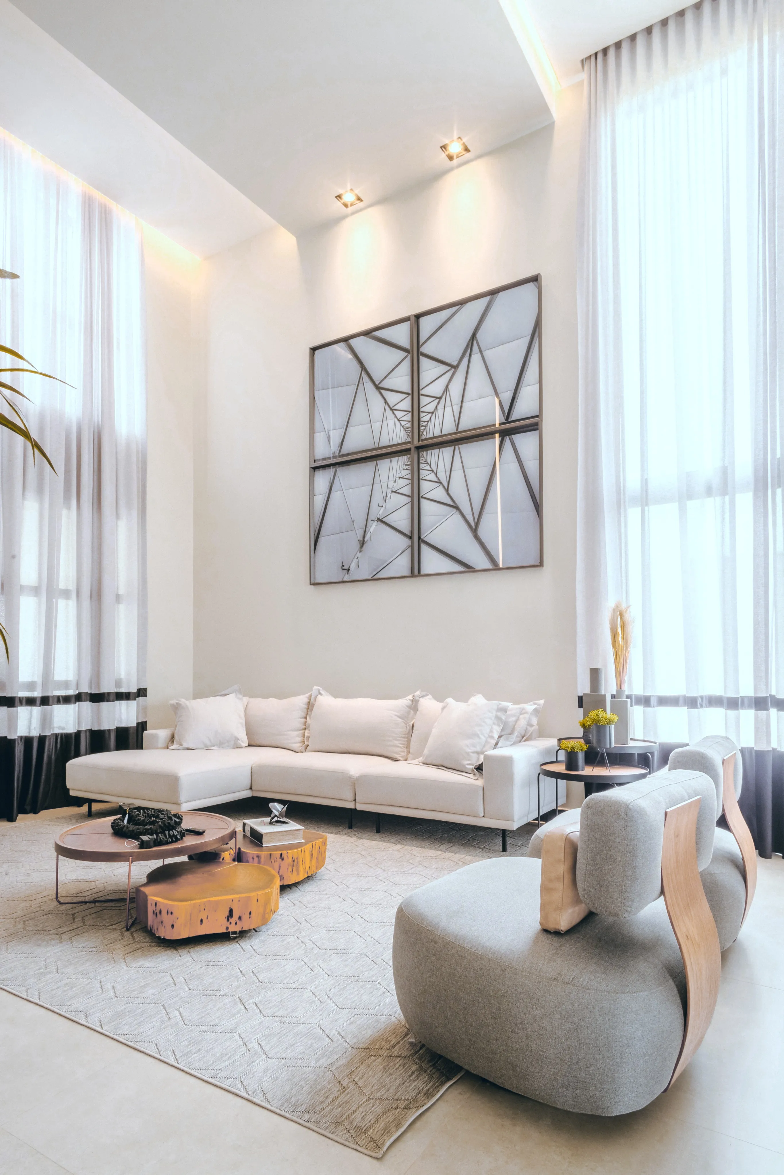 Double-height living room with a curved sofa, wooden coffee tables and abstract wall art