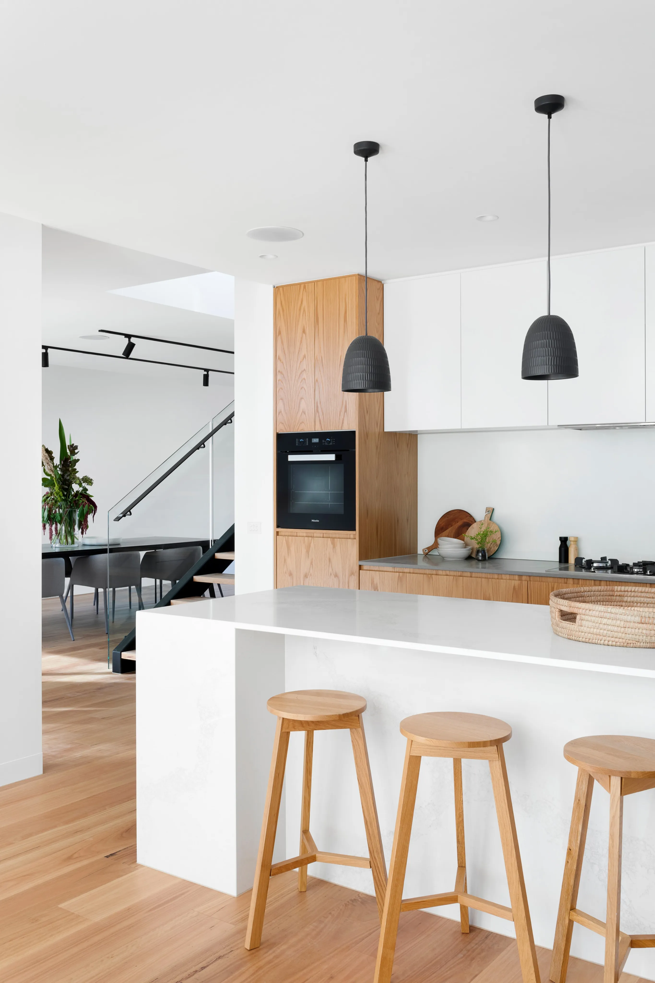 Kitchen with wooden cabinetry, a white breakfast bar and wooden stools